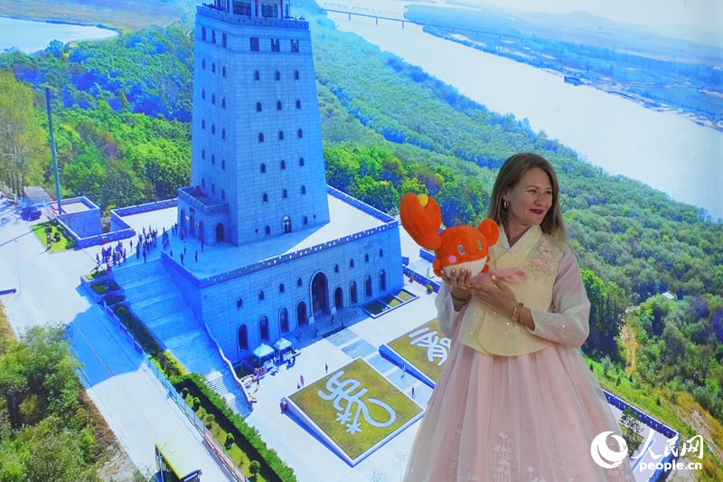 塔尼娅在延边展馆“一眼望三国”背景板前打卡拍照。人民网记者 李洋摄