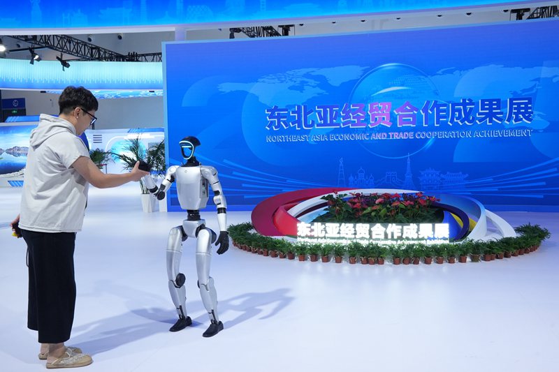 游客在东北亚经贸合作成果展上与机器人握手。人民网记者 李洋摄